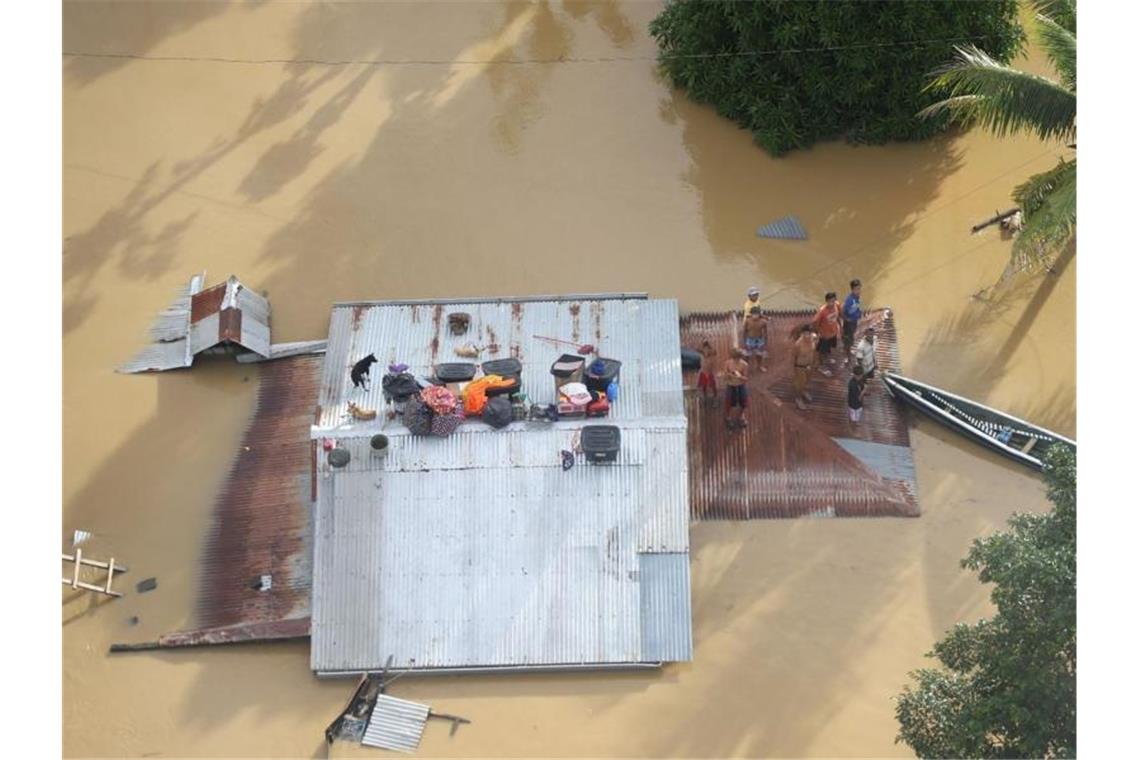 Menschen stehen auf dem Dach eines überfluteten Hauses bei Cagayan auf den Philippinen. Foto: Uncredited/Philippine Coast Guard/AP/dpa