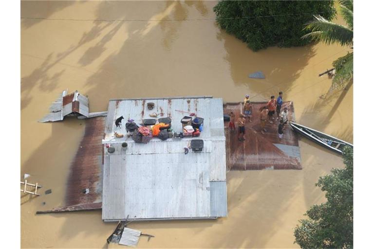 Menschen stehen auf dem Dach eines überfluteten Hauses bei Cagayan auf den Philippinen. Foto: Uncredited/Philippine Coast Guard/AP/dpa