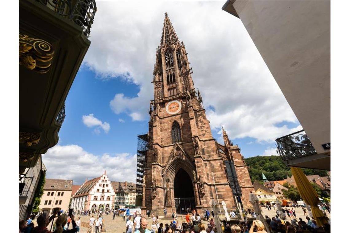 Südwest-Tourismus schrumpft wegen Corona weiter Menschen stehen auf dem Freiburger Münsterplatz vor dem Münster. Foto: Philipp von Ditfurth/dpa/Bildarchiv