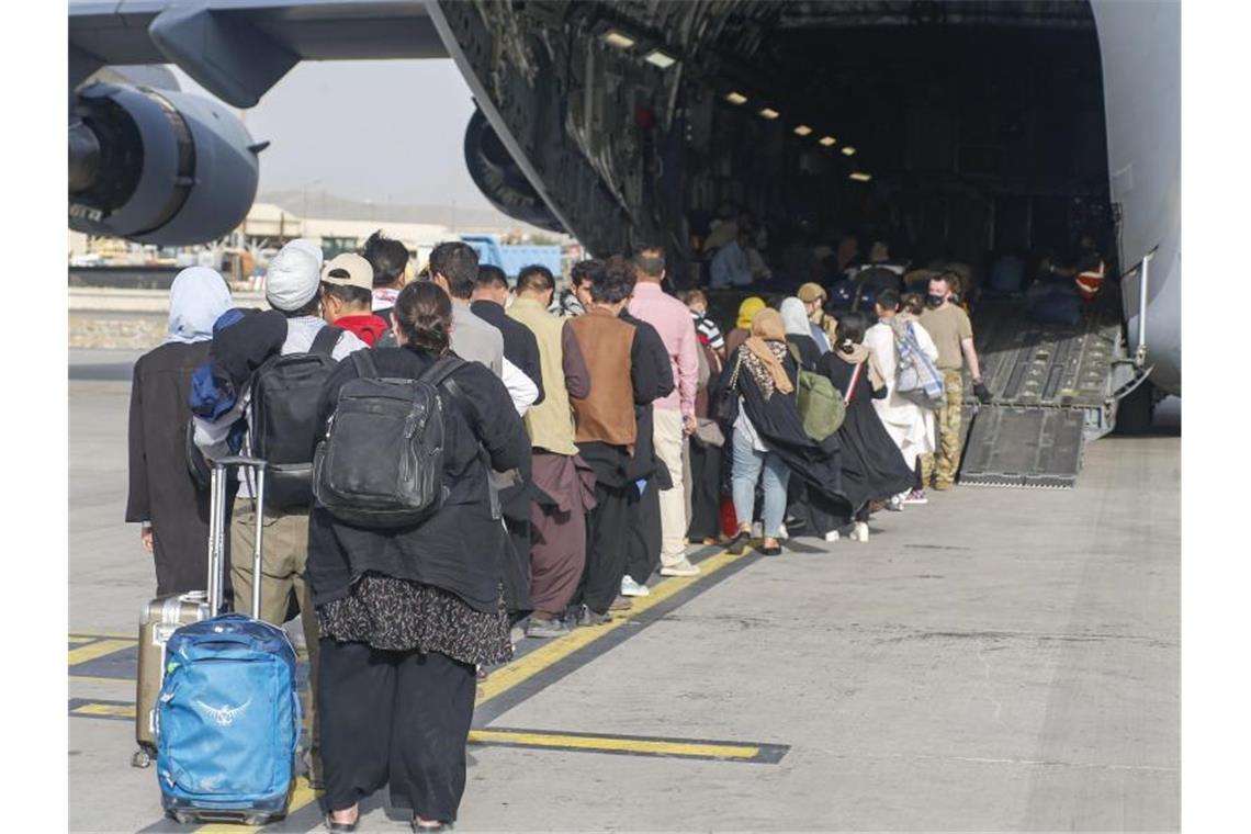 Menschen stehen auf dem Rollfeld und gehen an Bord eines US-Transportflugzeugs von Typ C-17 Globemaster III während ihrer Evakuierung am Hamid Karzai International Airport in Afghanistan. Foto: U.S. Marines/ZUMA Press Wire Service/dpa