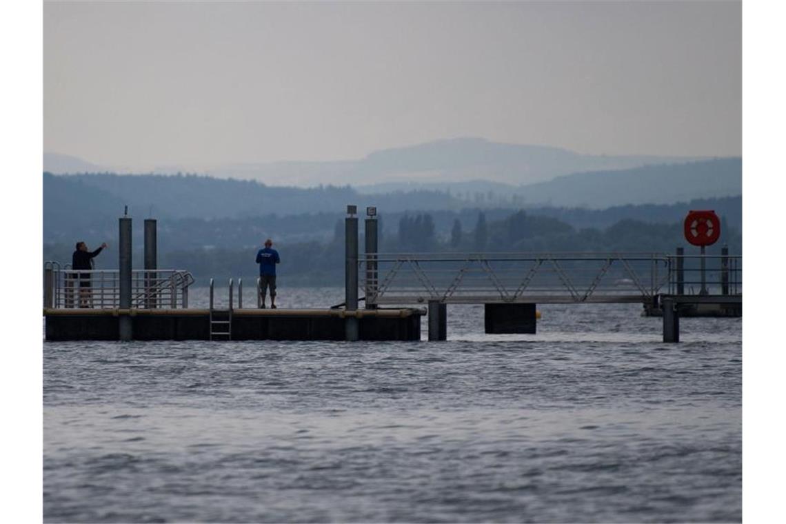 Tödliche Badeausflüge: Drei Schwimmer sterben Menschen stehen auf einem Steg am Ufer des Bodensees in Sipplingen. Foto: Marijan Murat/Archivbild