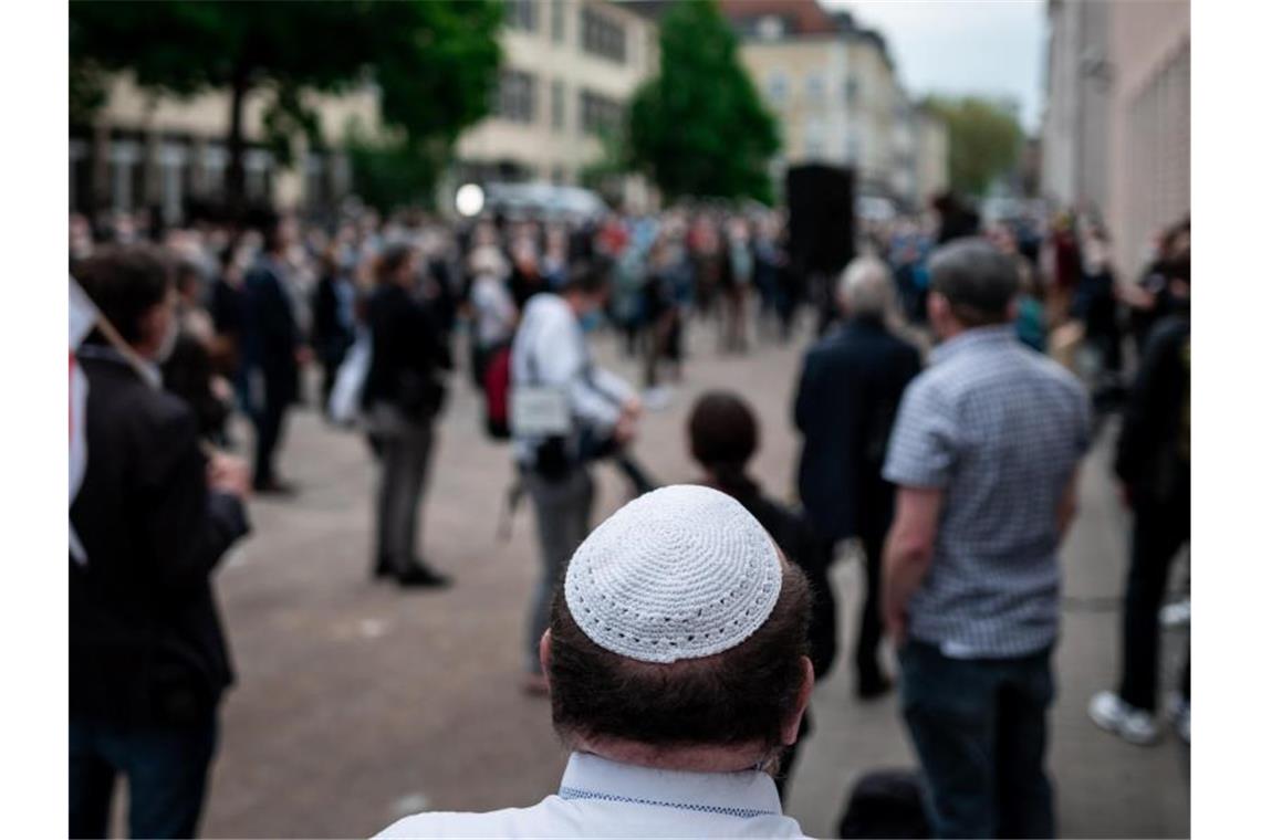 Scharfe Kritik an antisemitischen Übergriffen Menschen stehen bei einer Solidaritätskundgebung in Gelsenkirchen auf dem Platz vor der Synagoge. Dabei trägt ein Mann eine Kippa. Foto: Fabian Strauch/dpa