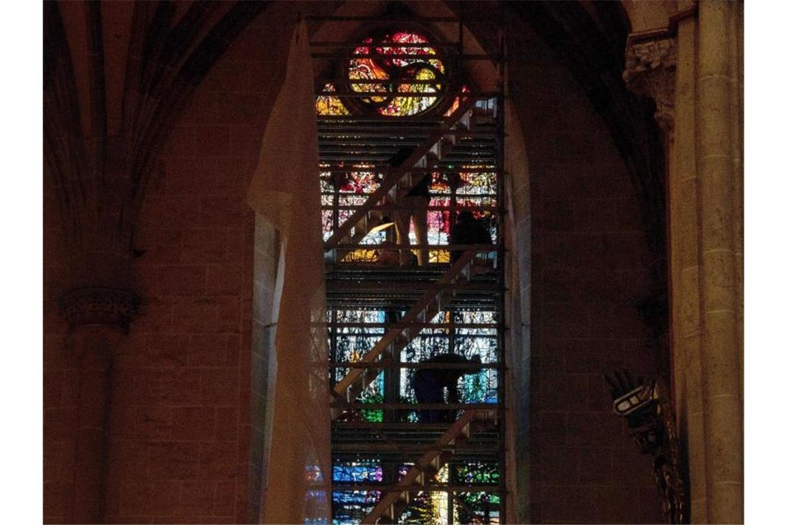 Neue Farbfenster im Ulmer Münster eingebaut Menschen stehen im Ulmer Münster auf einem Gerüst vor einem Kirchenfenster. Foto: Stefan Puchner/dpa