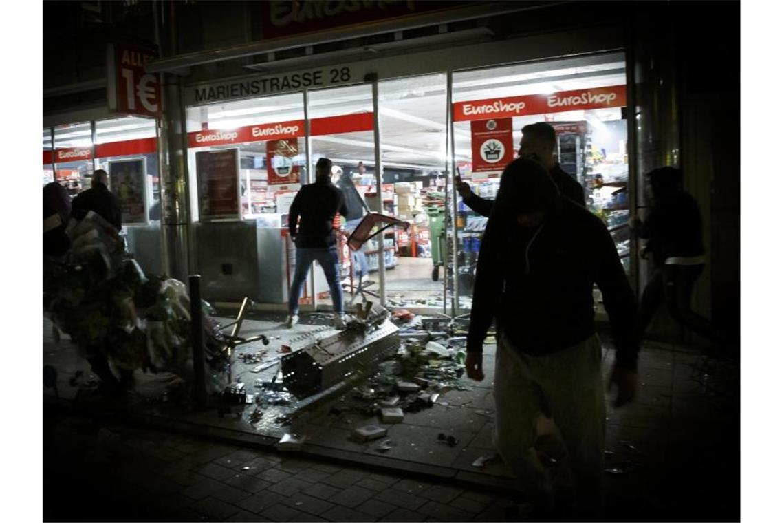 Menschen stehen in der Krawallnacht vor einem geplünderten Geschäft in der Stuttgarter Innenstadt. Foto: Julian Rettig/dpa