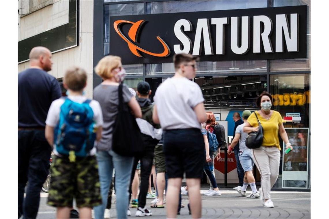 Media Markt und Saturn spüren Nachholbedarf der Kunden Menschen stehen in einer Warteschlange in Köln vor einer Filiale des Elektrohändlers Saturn an. Foto: Marius Becker/dpa