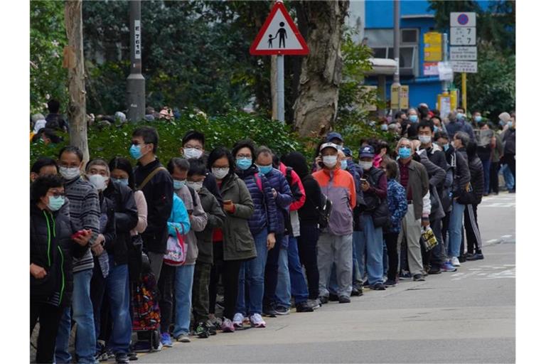 Menschen stehen in Hongkong an, um Schutzmasken zu kaufen. Foto: Vincent Yu/AP/dpa