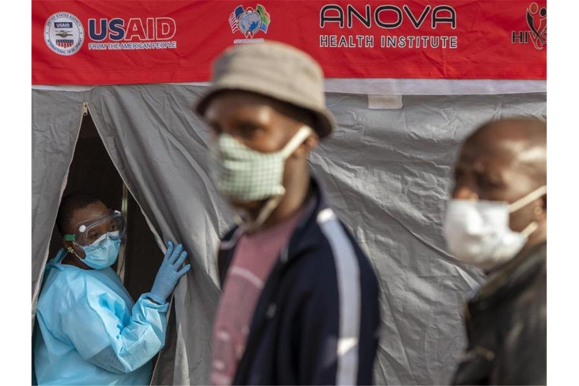 Menschen stehen in Johannesburg vor einem Zelt an, um sich auf eine Infektion mit dem Coronavirus testen zu lassen. Foto: Themba Hadebe/AP/dpa