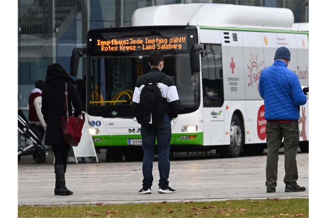Menschen stehen in Salzburg in einer Warteschlange vor einem Impfbus. Foto: Barbara Gindl/APA/dpa