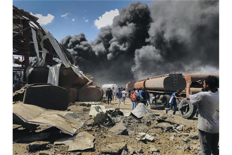 Menschen stehen nach einem Luftangriff auf die Hauptstadt der Region Tigray im Norden Äthiopiens vor schwarzen Rauchschwaden. Foto: UGC/AP/dpa/Archiv