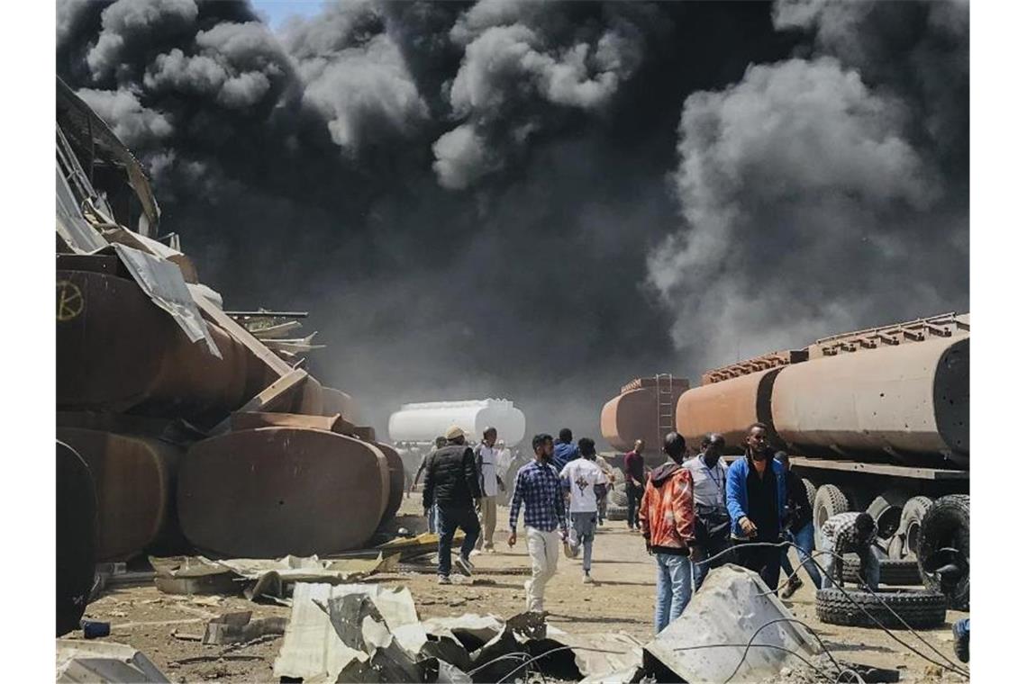 Menschen stehen nach einem Luftangriff auf die Hauptstadt der Region Tigray im Norden Äthiopiens vor schwarzen Rauchschwaden. Foto: ---/UGC/AP/dpa