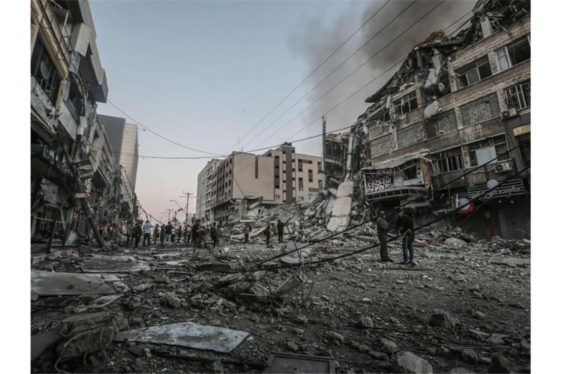 Rund 1750 Raketenabschüsse auf Israel - Viele Tote in Gaza Menschen stehen vor dem eingestürzten Al-Shorouk Tower, nachdem dieser bei einem israelischen Luftangriff getroffen wurde. Foto: Mohammed Talatene/dpa