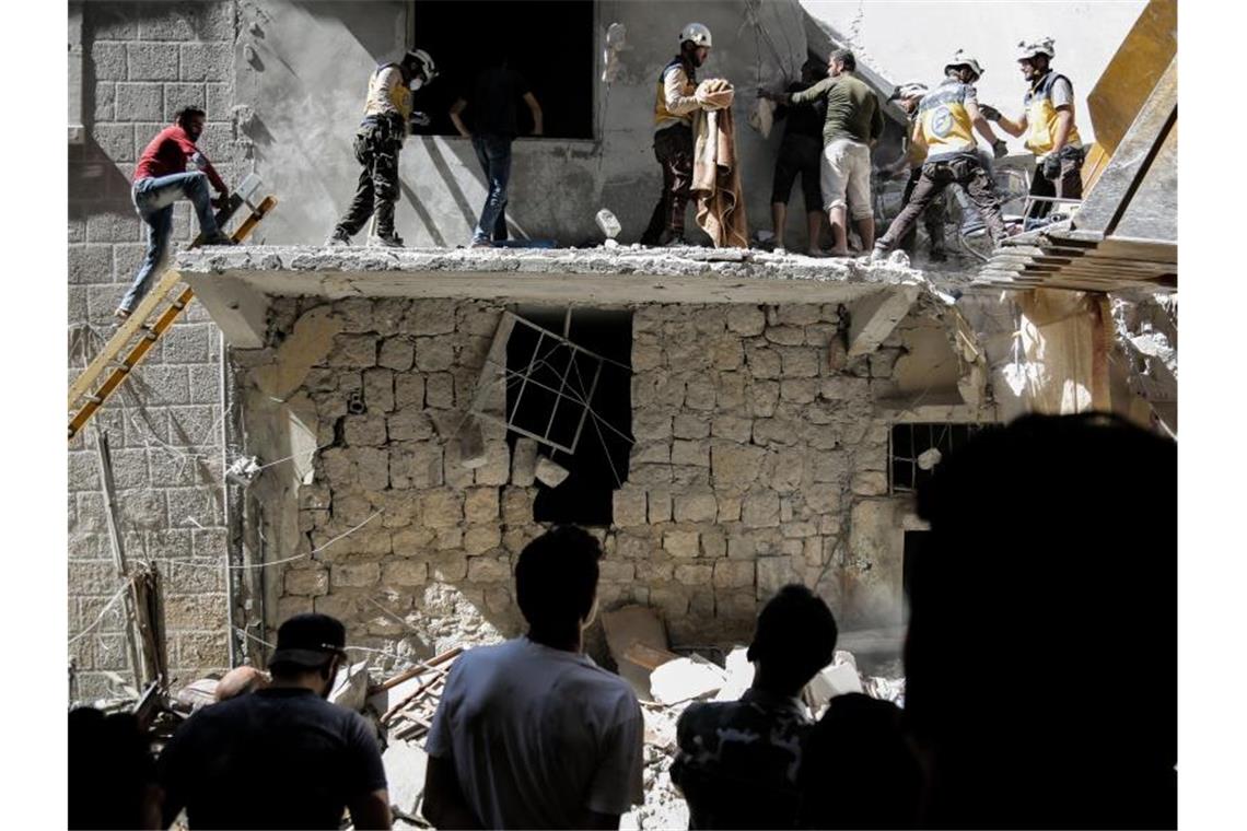 Menschen stehen vor einem Gebäude, das bei einem Luftangriff am 27. Mai durch die syrischen Regierungskräfte beschädigt wurde. Foto: Anas Alkharboutli