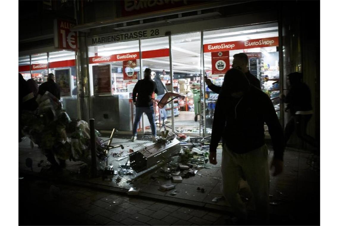 Menschen stehen vor einem geplünderten Geschäft in der Marienstraße. Foto: Julian Rettig/dpa/Archivbild