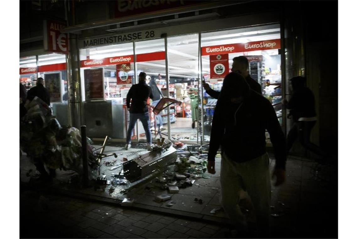 Menschen stehen vor einem geplünderten Geschäft in der Marienstraße. Foto: Julian Rettig/dpa