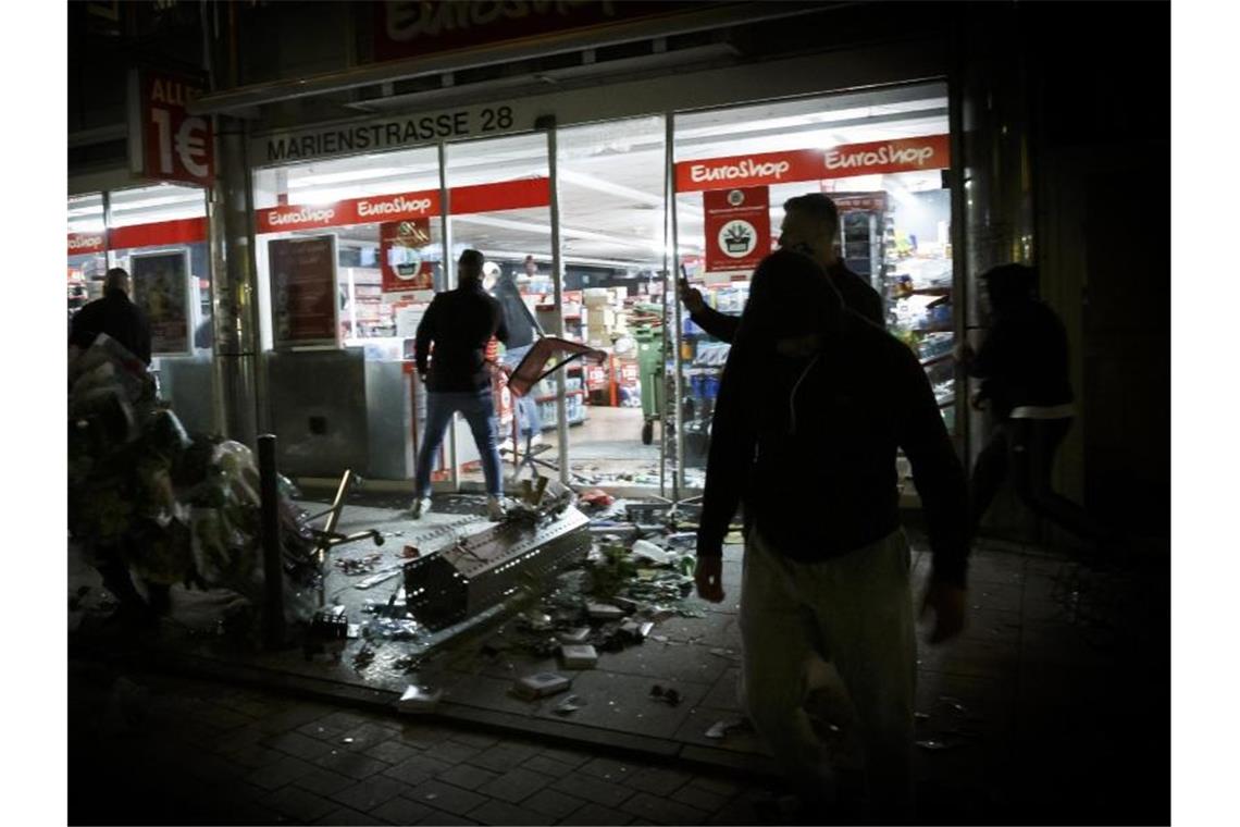 Menschen stehen vor einem während der Krawalle geplünderten Geschäft in der Marienstraße. Foto: Julian Rettig/dpa/Archivbild