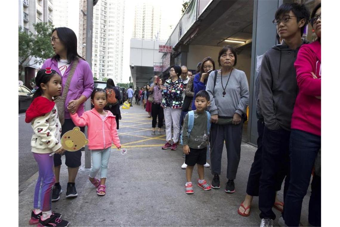 Hongkong: Demokratie-Lager liegt bei Bezirkswahlen vorn Menschen stehen vor einem Wahllokal, um ihre Stimme bei den Bezirksratswahlen abzugeben. Foto: Ng Han Guan/AP/dpa