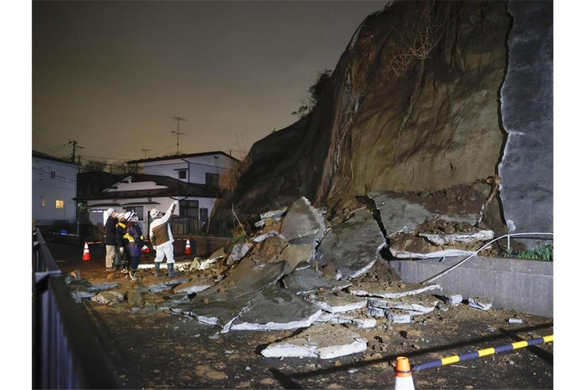 Starkes Erdbeben in Japan - vorübergehend Tsunami-Warnung Menschen stehen vor eingestürzten Teilen einer Klippe. Eine Tsunami-Warnung in Folge eines starken Erdbebens im Nordosten Japans ist wieder aufgehoben worden. Foto: ---/Kyodo/dpa