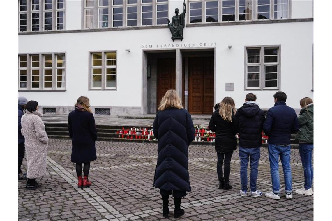 Heidelberg gedenkt der Opfer des Amoklaufes an der Uni Menschen stehen zur Gedenkminute vor dem Haupteingang der Neuen Universität. Foto: Uwe Anspach/dpa