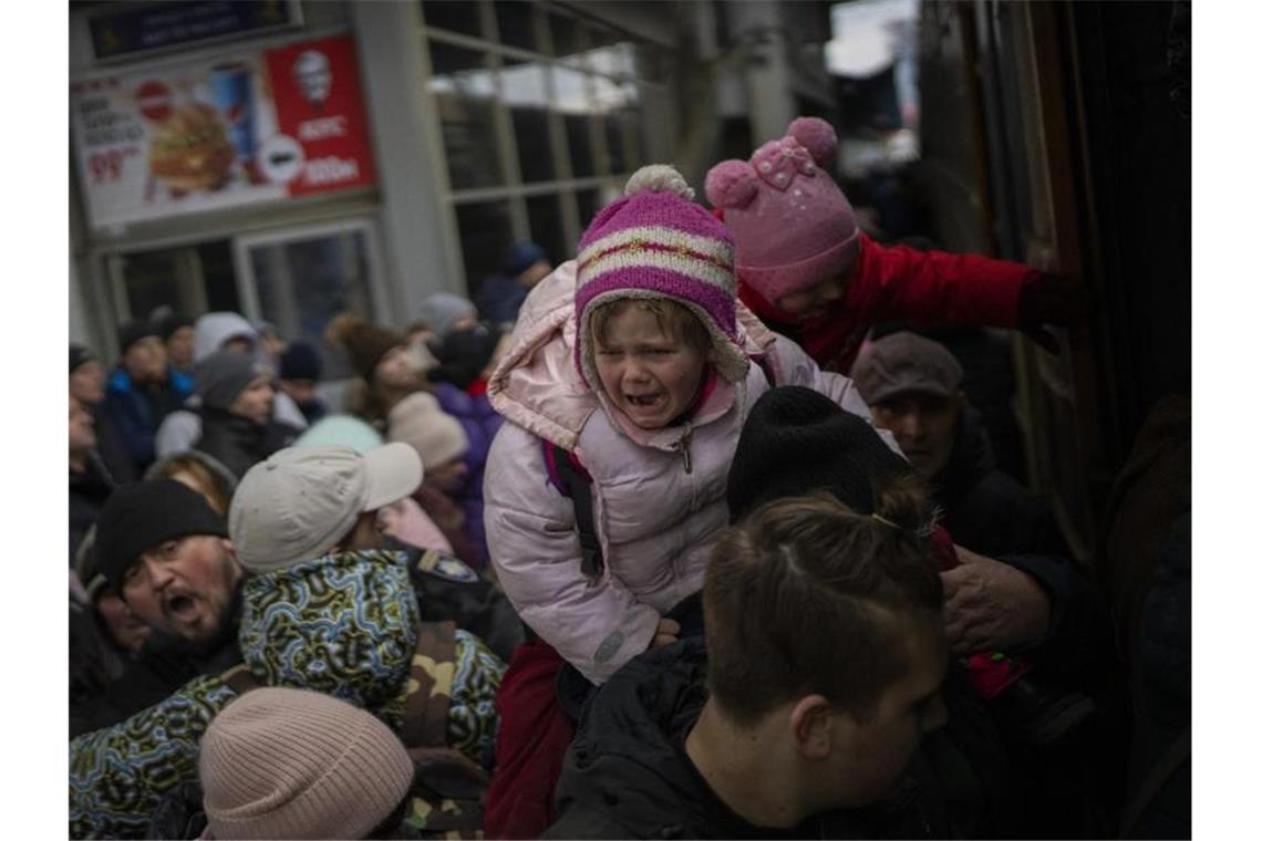 Warnung vor Gewalt an flüchtenden Frauen und Kindern Menschen tragen ihre Kinder und versuchen am Bahnhof von Kiew, in einen Zug nach Lwiw zu steigen. Foto: Emilio Morenatti/AP/dpa