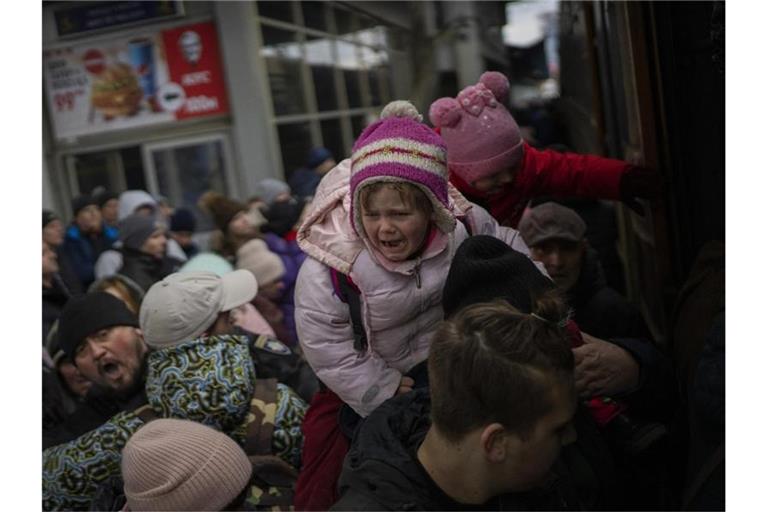 Menschen tragen ihre Kinder und versuchen am Bahnhof von Kiew, in einen Zug nach Lwiw zu steigen. Foto: Emilio Morenatti/AP/dpa