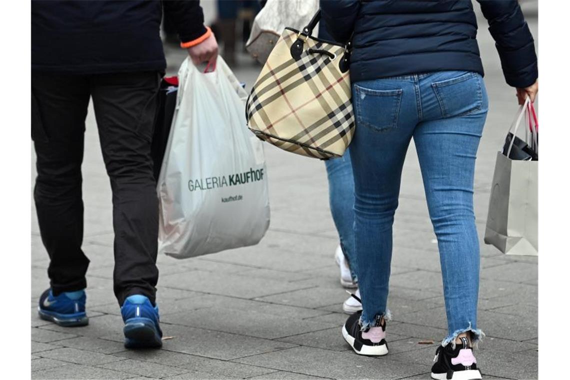 Menschen tragen in einer Einkaufsstraße Taschen und Tüten. Foto: Henning Kaiser/dpa