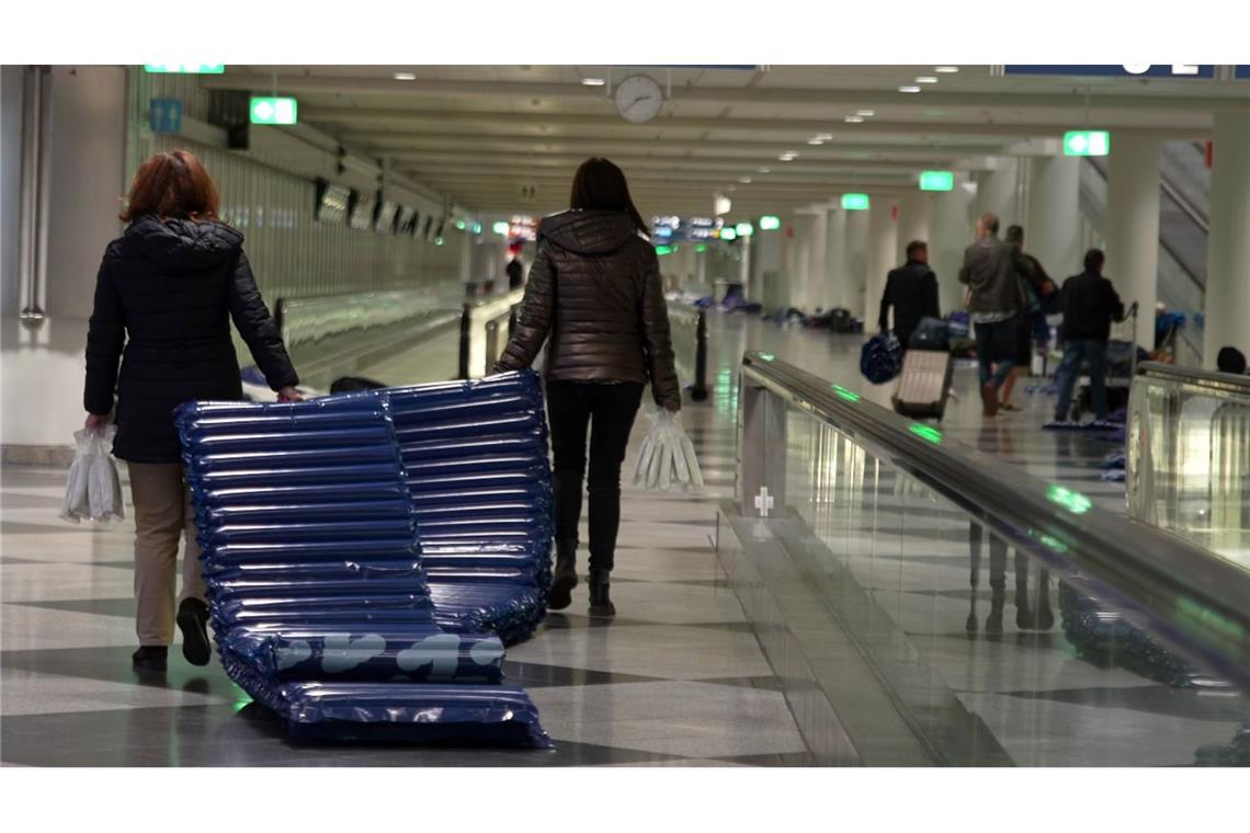 Menschen tragen nach möglichen Drohnensichtungen am Flughafen München Luftmatratzen.