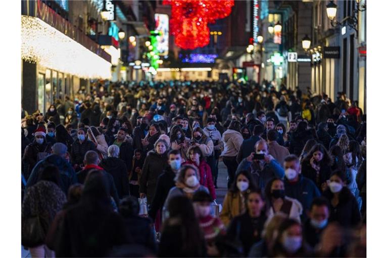 Menschen tragen Schutzmasken gehen durch die Innenstadt in Madrid. Foto: Bernat Armangue/AP/dpa