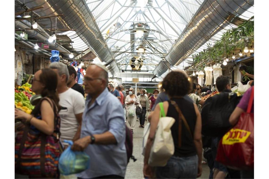 Menschen tragen Schutzmasken, während sie auf dem Mahane Yehuda Markt in Jerusalem einkaufen. Foto: Maya Alleruzzo/AP/dpa