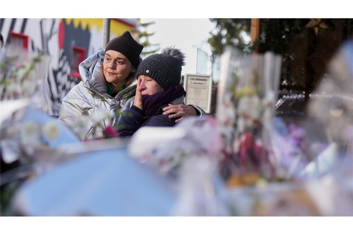 Menschen trauern hinter Blumen und Briefen in der Nähe der abgeriegelten Le Constellation Bar, wo ein verheerender Brand während der Neujahrsfeierlichkeiten Tote und Verletzte forderte.