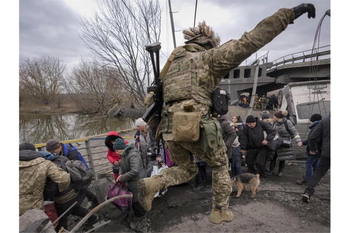 Russland setzt Angriff auf Mariupol fort Menschen überqueren den Fluss Irpin auf einem improvisierten Weg unter einer Brücke. Foto: Vadim Ghirda/AP/dpa