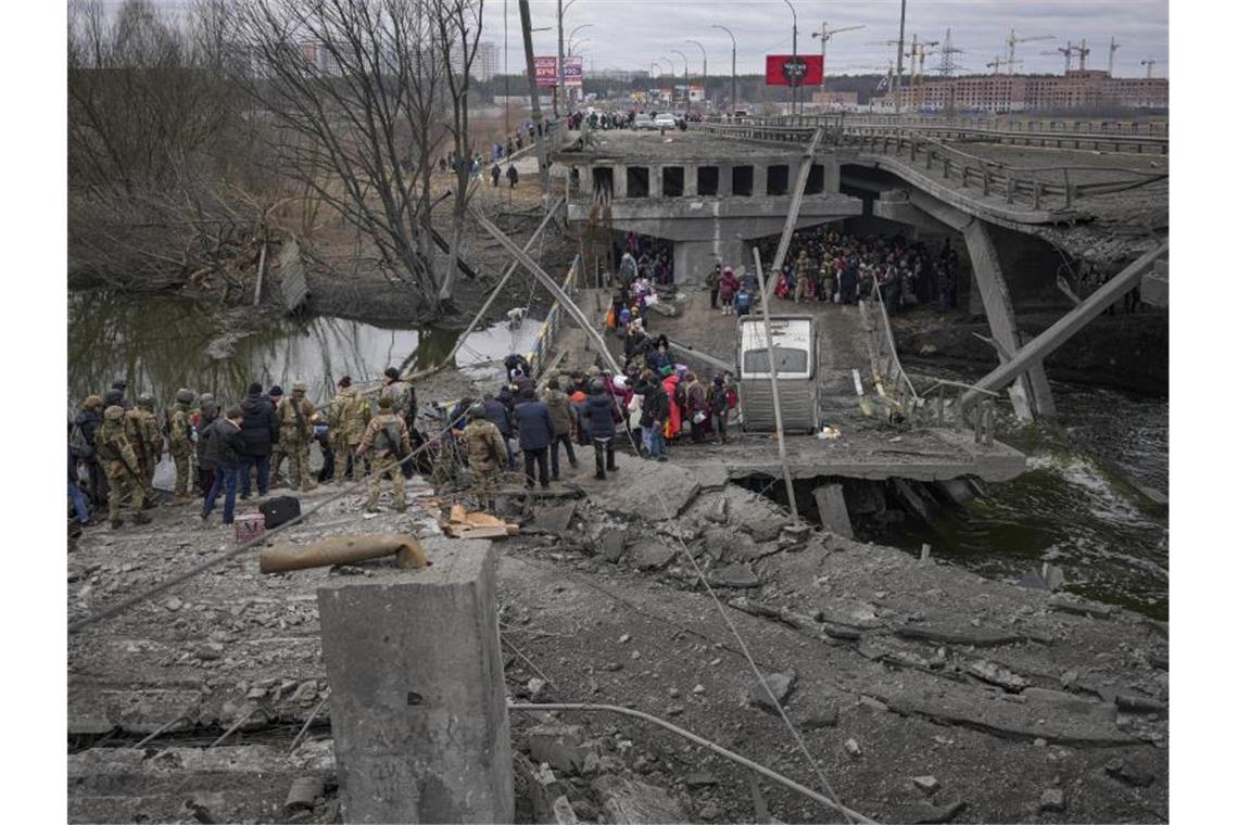 Russland setzt Angriff auf Mariupol fort Menschen überqueren den Fluss Irpin in der Ukraine auf einem improvisierten Weg. Foto: Vadim Ghirda/AP/dpa