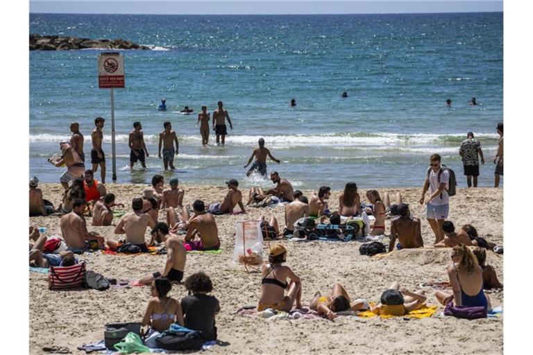 Menschen verbringen den Tag in der Sonne am Strand von Tel Aviv. Foto: Ilia Yefimovich/dpa