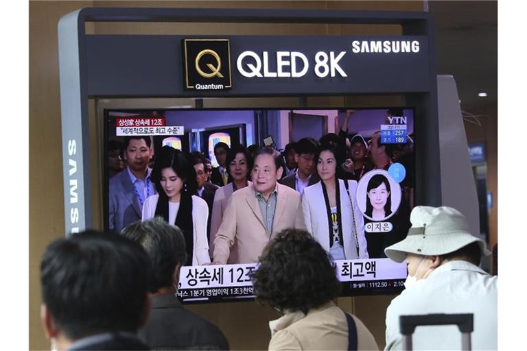 Menschen verfolgen in einer Bahnstation in Seoul eine Nachrichtensendung an einem TV-Gerät. Das Archivbild zeigt Lee Kun-Hee (M) und seine Töchter. Foto: Ahn Young-Joon/AP/dpa