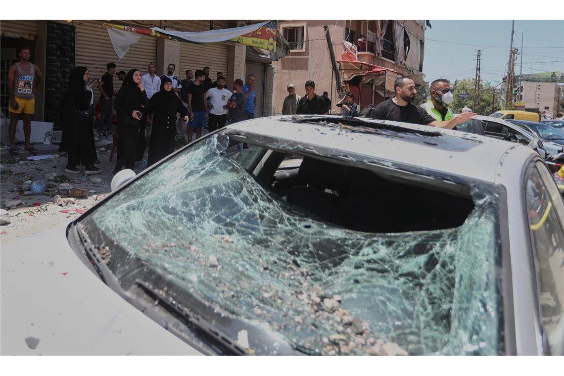 Menschen versammeln sich neben einem Auto, das bei einem israelischen Luftangriff in der Stadt Nabatieh im Südlibanon beschädigt wurde.