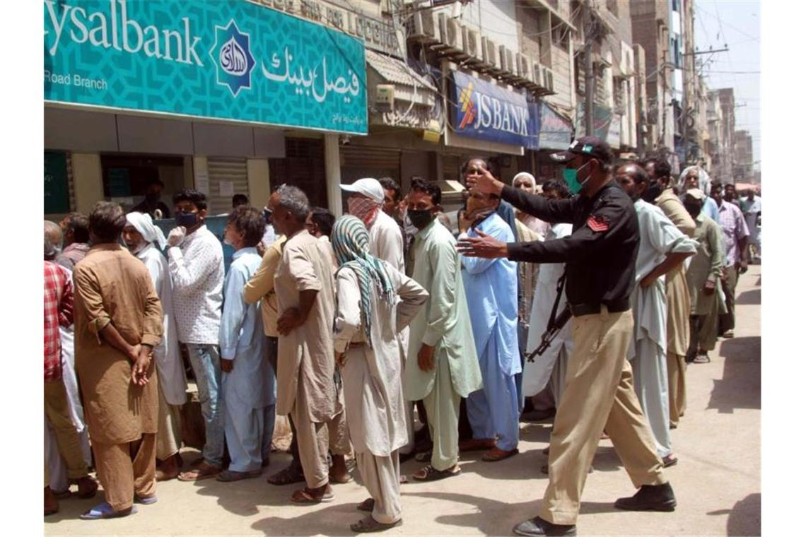 Menschen versammeln sich ohne Sicherheitsabstand vor einer Bank, um ihre Rechnungen für Versorgungsleistungen und aus anderen Gründen zu bezahlen. Foto: Ppi/PPI via ZUMA Wire/dpa