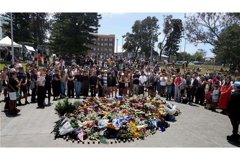 Menschen versammelt sich einen Tag nach einer Schießerei am Bondi Beach in Sydney um ein Blumendenkmal.