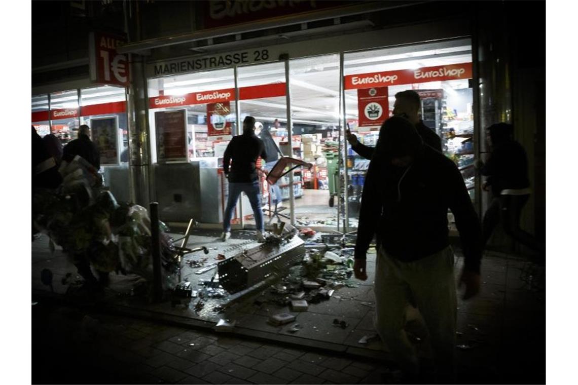 Partygänger randalieren in Stuttgart Menschen vor einem geplünderten Geschäft in der Marienstraße in Stuttgart. Foto: Julian Rettig/dpa