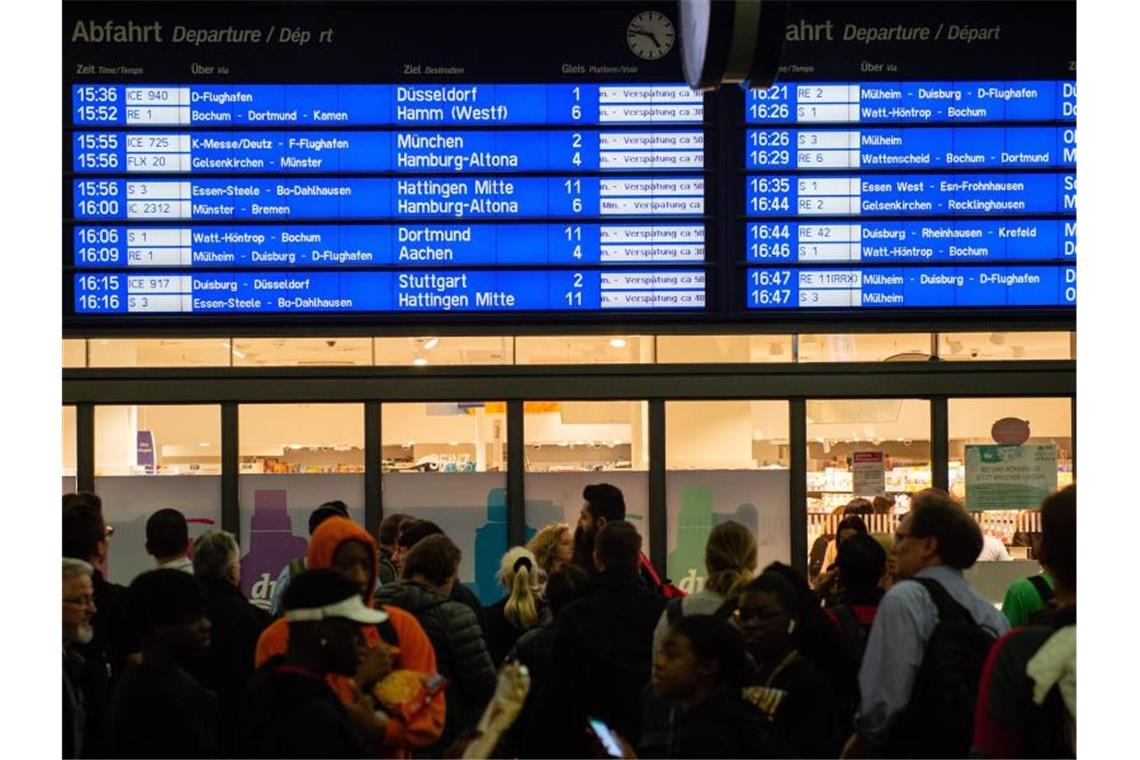 Menschen warten im Essener Hauptbahnhof vor der Anzeigetafel, auf der zahlreiche Zugverspätungen angegeben werden. Foto: Lisa Ducret/dpa