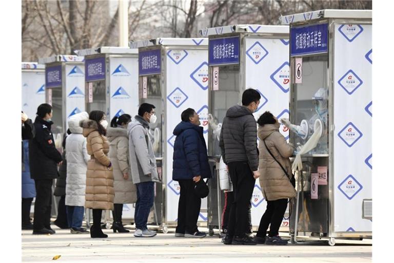 Menschen warten im Pekinger Stadtbezirk Xicheng im Rahmen eines Corona-Massentests vor Test-Kabinen. Foto: -/kyodo/dpa