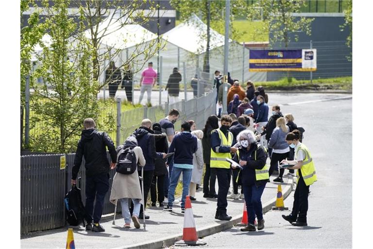 Menschen warten in einer Schlange vor dem mobilen Covid-Impfzentrum an der ESSA-Akademie in Bolton. Foto: Danny Lawson/PA Wire/dpa
