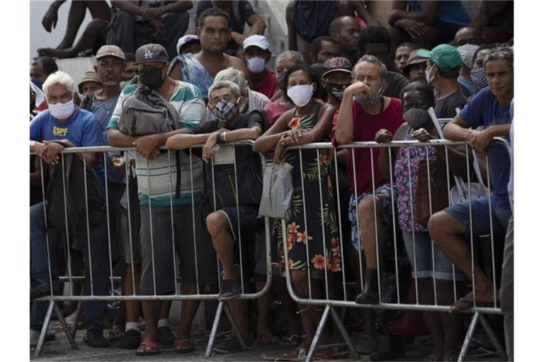 Menschen warten in Rio de Janeiro in einer Schlange auf eine kostenlose Mahlzeit. Foto: Silvia Izquierdo/AP/dpa