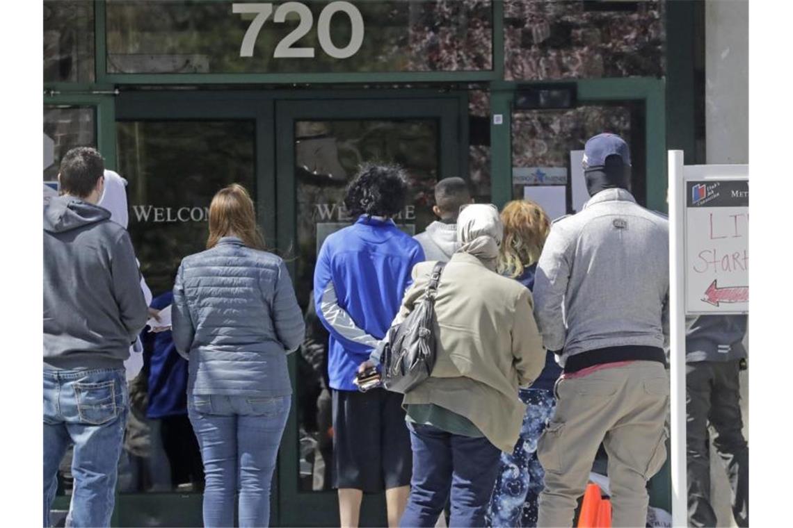 Menschen warten vor einem Arbeitsamt. Die US-Wirtschaft ist im ersten Quartal wegen der Coronavirus-Pandemie geschrumpft. Foto: Rick Bowmer/AP/dpa