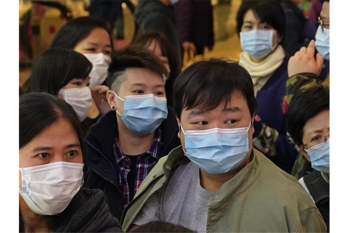 Menschen warten vor einem Geschäft in Hongkong, um Atemschutzmasken zu kaufen. Foto: Vincent Yu/AP/dpa