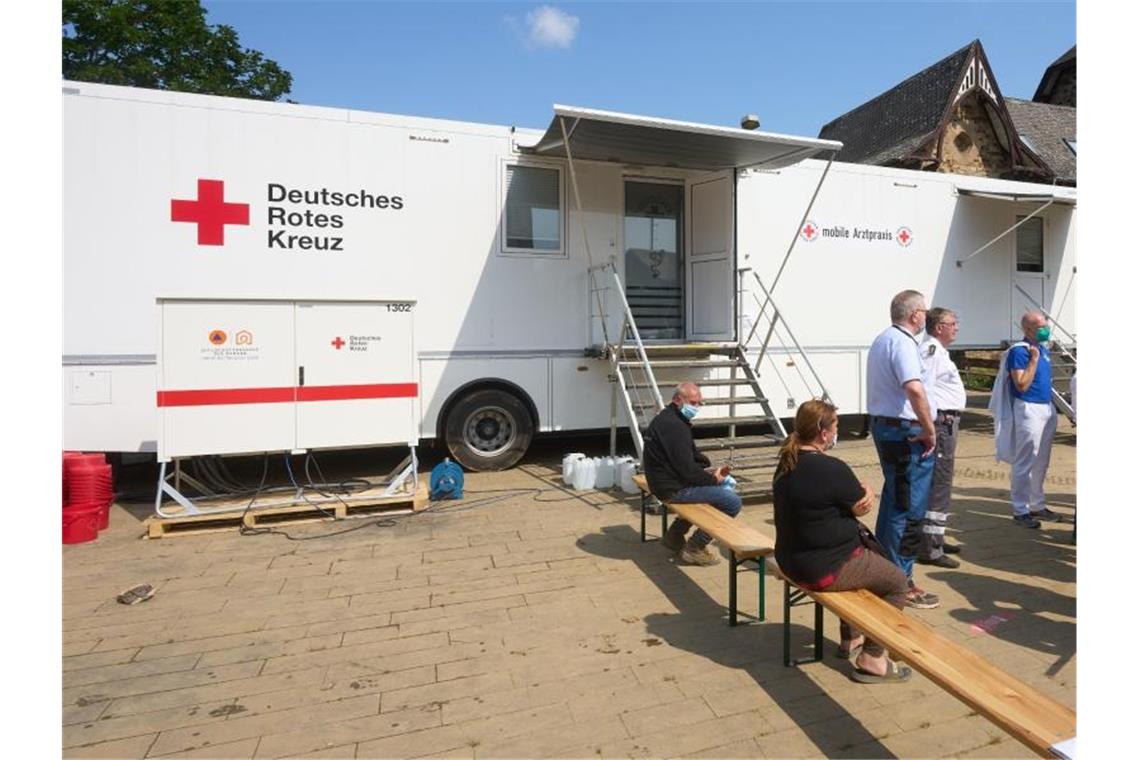 Menschen warten vor einer mobilen Arztpraxis des Deutschen Roten Kreuzes in Bad Neuenahr-Ahrweiler. Foto: Thomas Frey/dpa