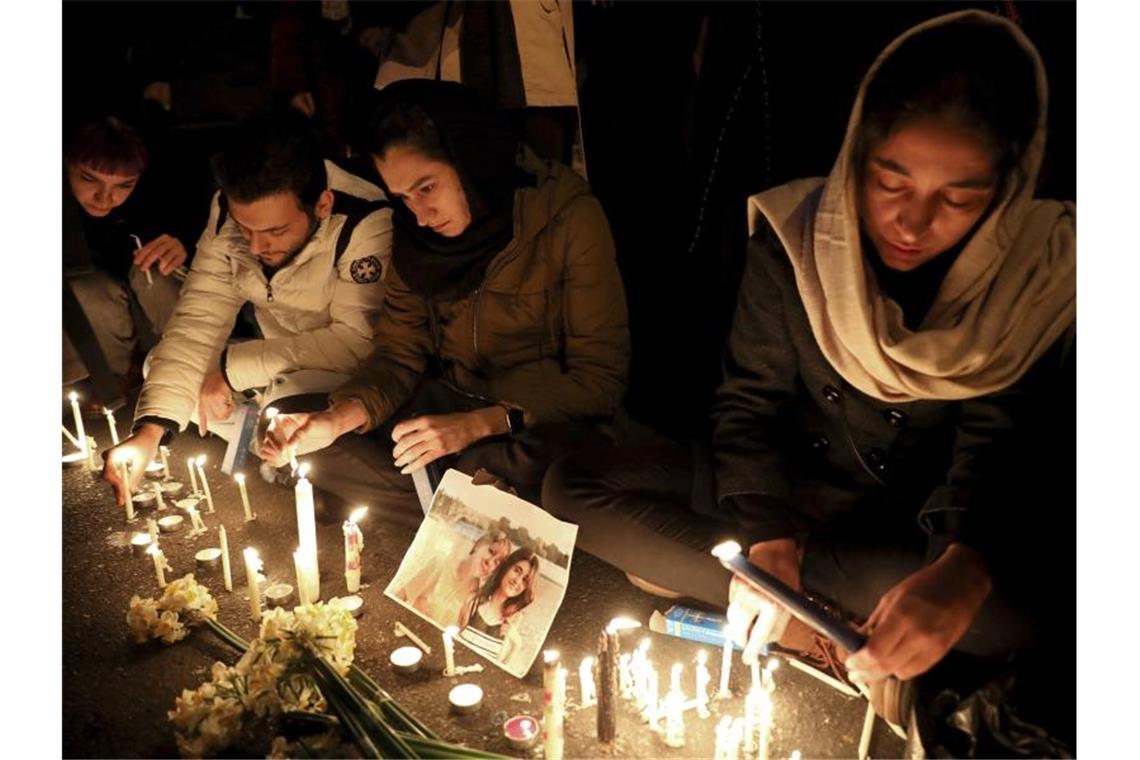 Menschen zünden bei einer Mahnwache am Eingang der Amri Kabir Universität in Teheran Kerzen an, um der Opfer des Flugzeugabsturzes zu gedenken. Foto: Ebrahim Noroozi/AP/dpa