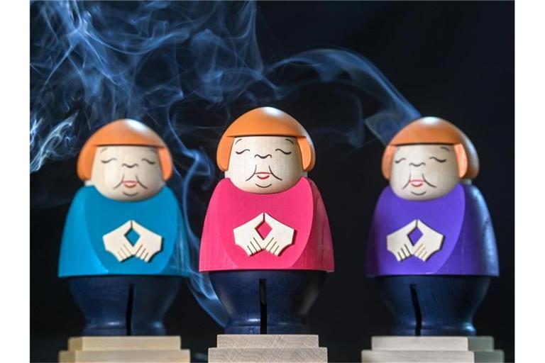 Merkel Räucherfiguren rauchen in der Schauwerkstatt der Seiffner Volkskunst. Foto: Hendrik Schmidt/dpa-Zentralbild/ZB