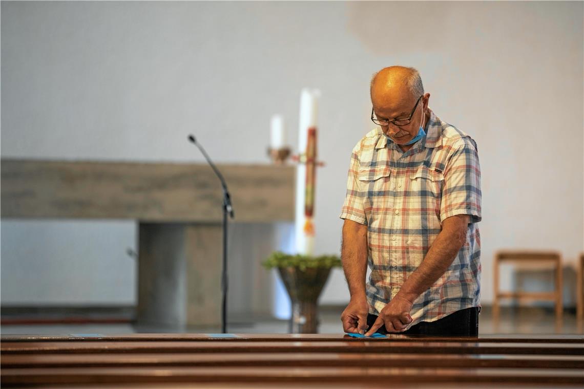 Mesner Antonio Vizziello markiert mögliche Sitzplätze in den Bankreihen der katholischen Kirche Christkönig in der Marienburger Straße in Backnang. Für Familien soll die Möglichkeit geschaffen werden, im Gottesdienst nebeneinander zu sitzen. Foto: A. Becher