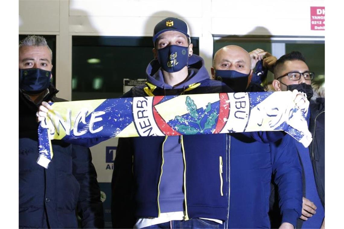 Mesut Özil (M.) am Flughafen in Istanbul mit einem Fenerbahce-Schal. Foto: Str/AP/dpa