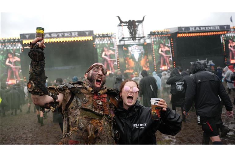 Metalfans feiern nach der Öffnung des sogenannten "Infield" vor den beiden Hauptbühnen auf dem Festivalgelände des Wacken Open Airs.