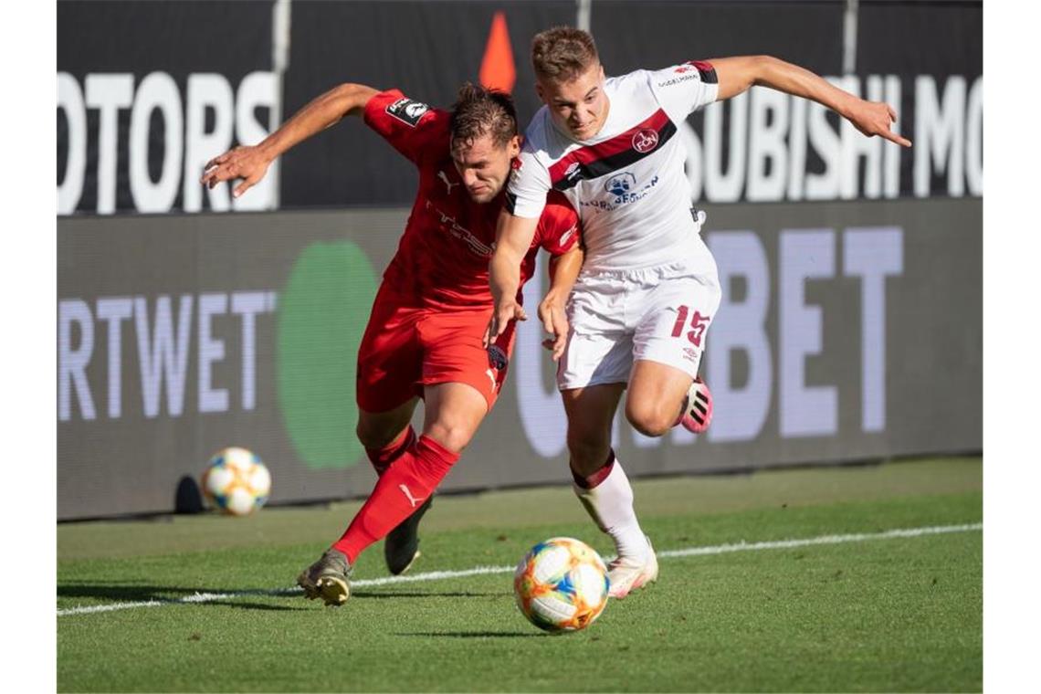 Michael Heinloth von Ingolstadt (l) und Fabian Nürnberger von Nürnberg im Kampf um den Ball. Foto: Matthias Balk/dpa